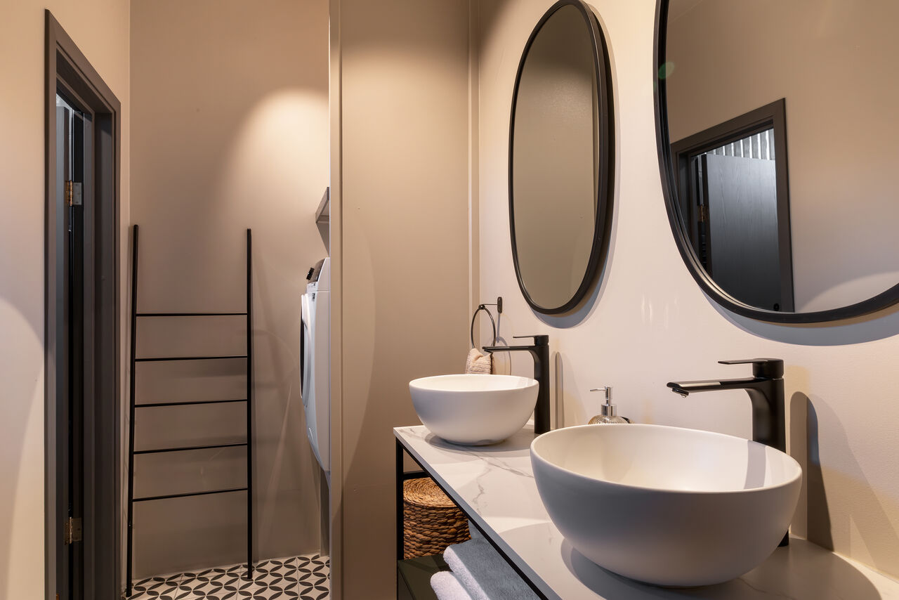 A bathroom with a vessel sink and round mirror
