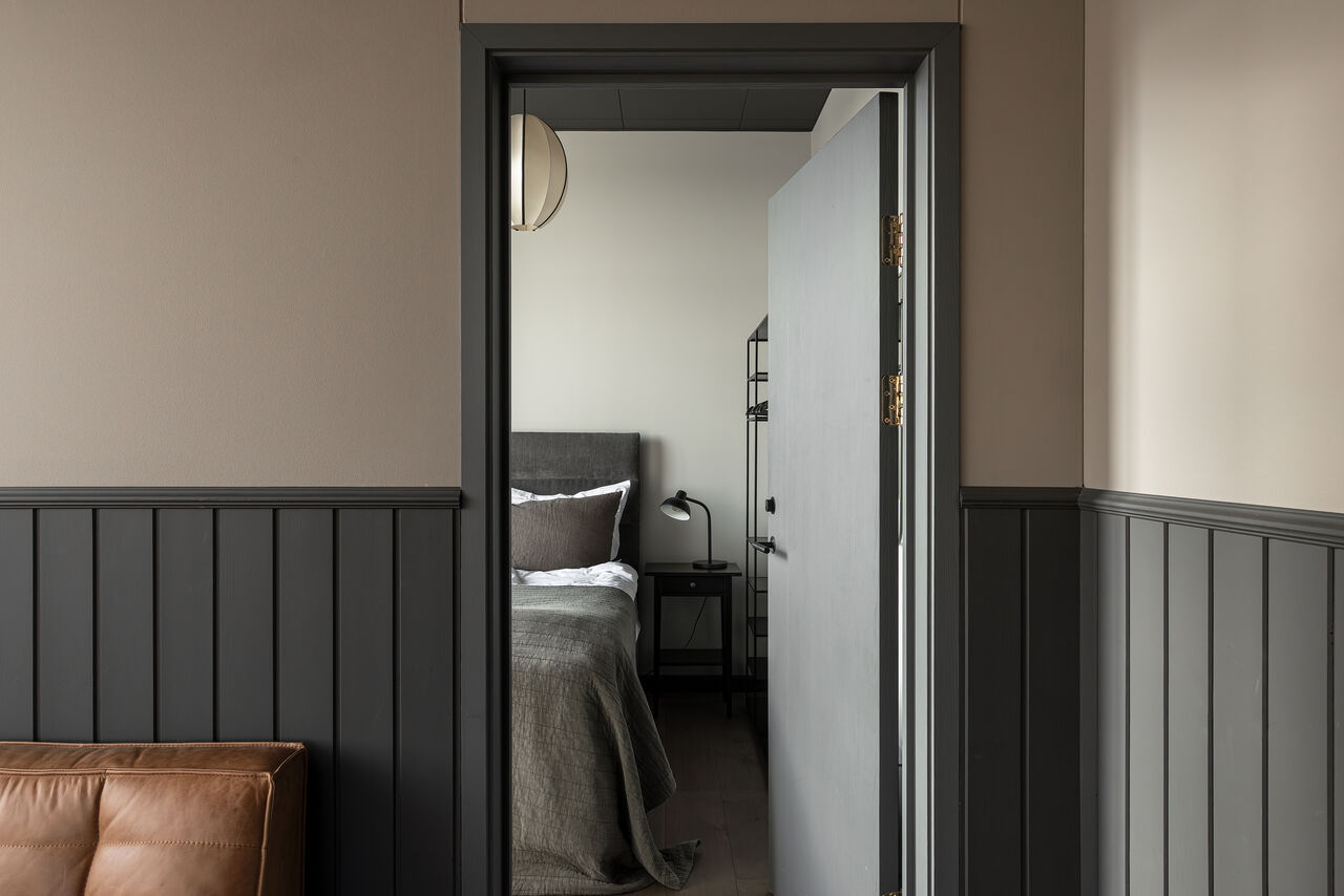 The hallway through to a bedroom, past dark wood panelling