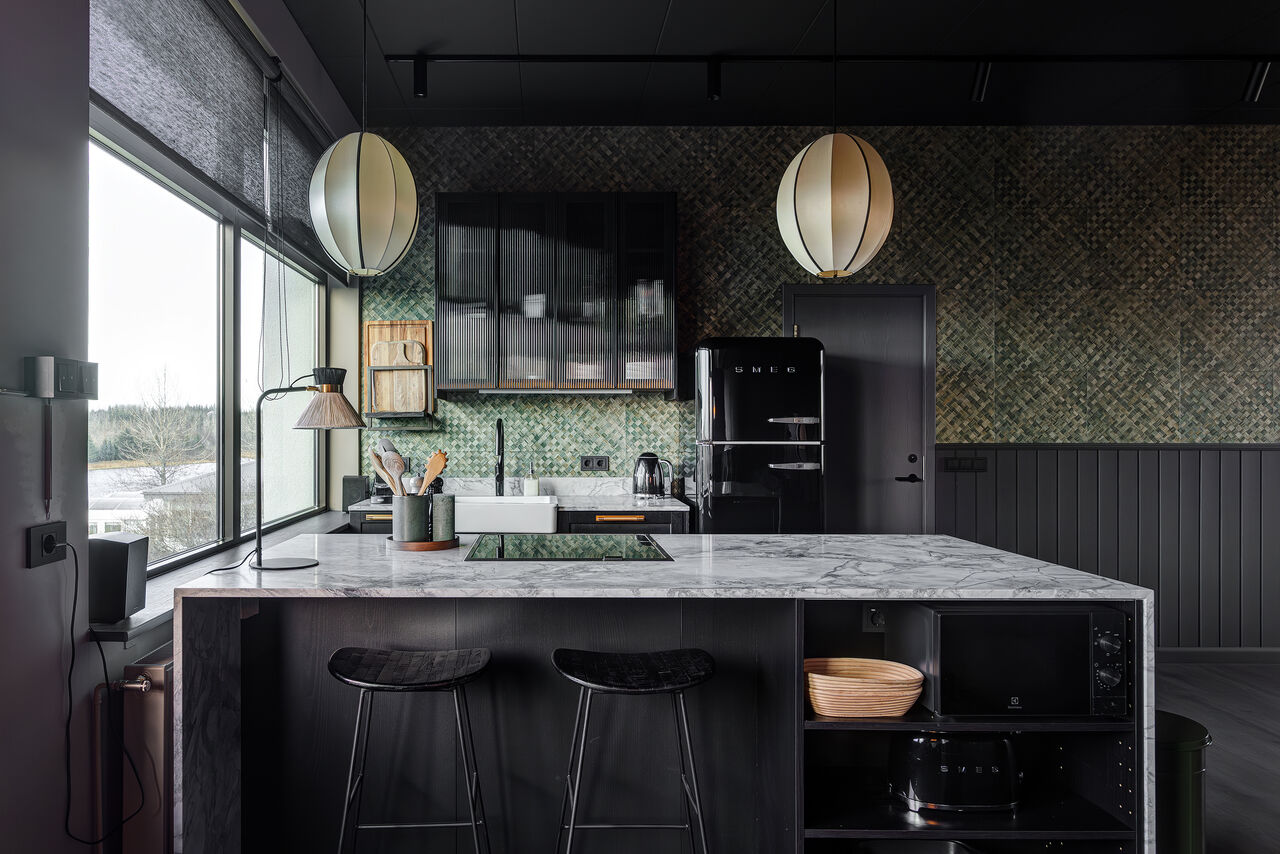 The Penthouse's charcoal kitchen with a marble island and rattan pendants