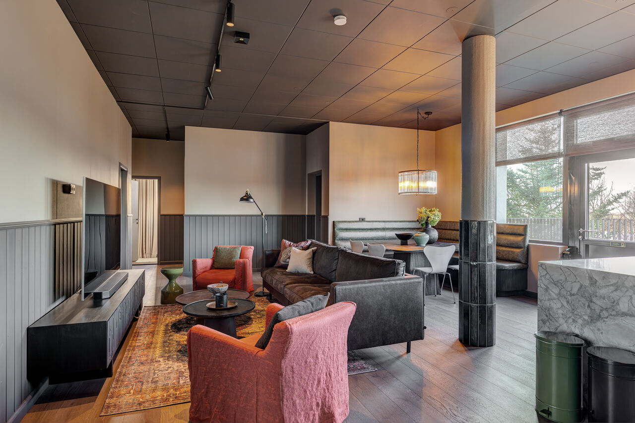 The Penthouse's open-plan living room in charcoal and rust, with a marble kitchen island