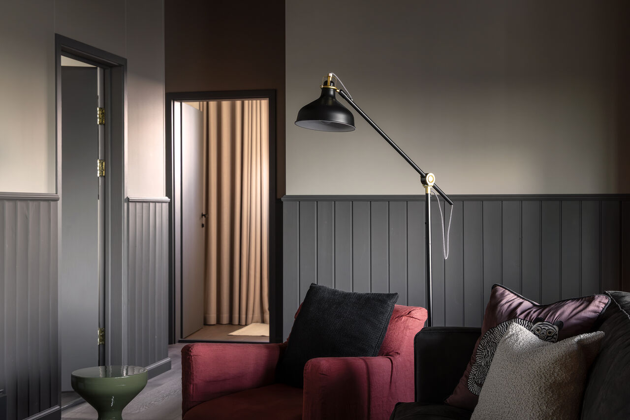 A reading corner with a crimson armchair and a black floor lamp