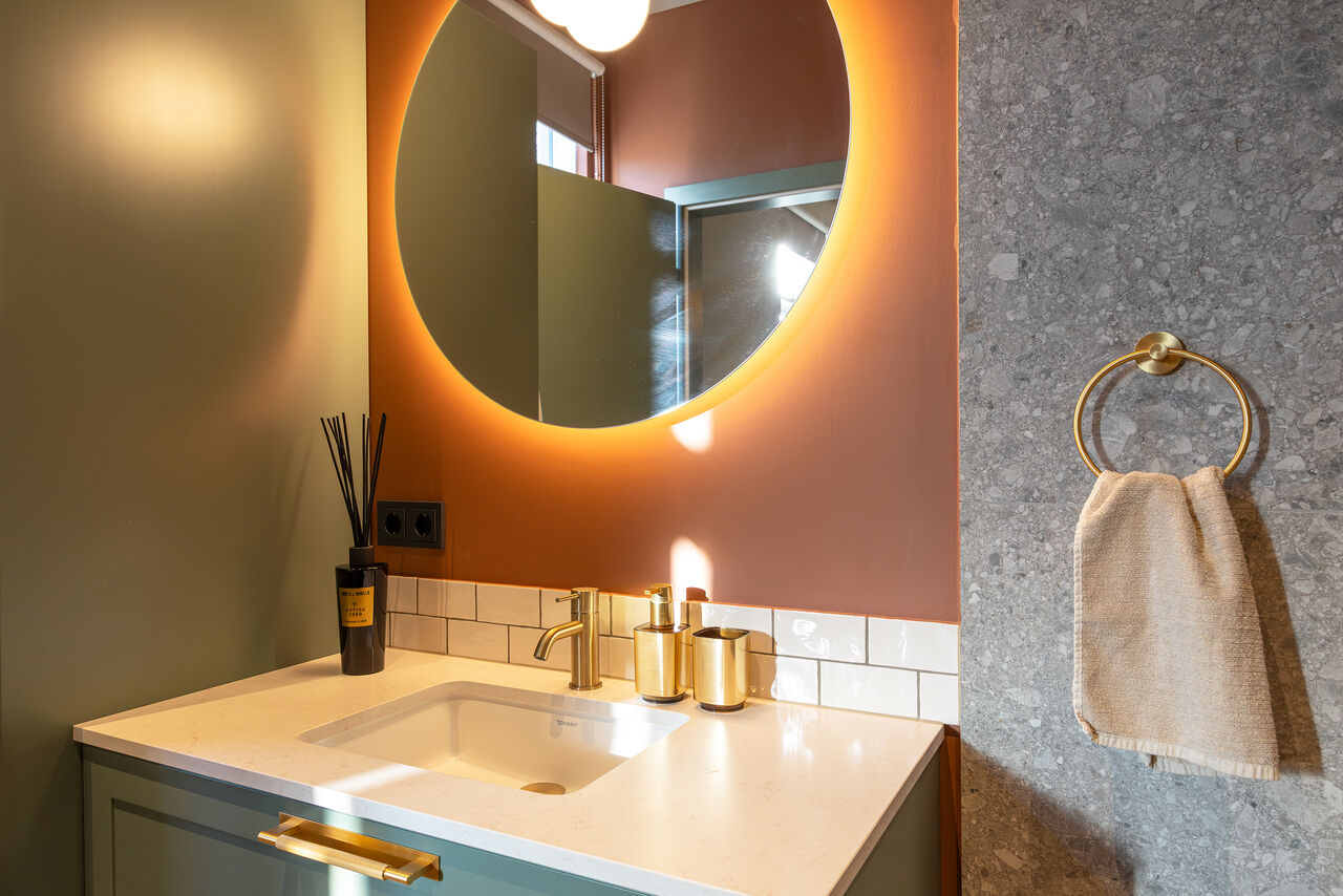 A terracotta bathroom with a backlit round mirror