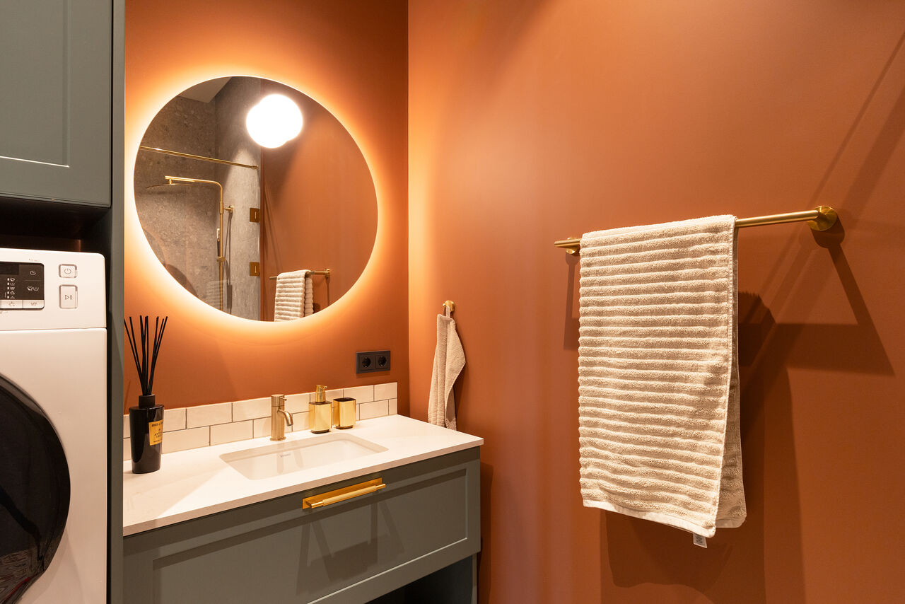 A terracotta bathroom with a washer/dryer beside the basin