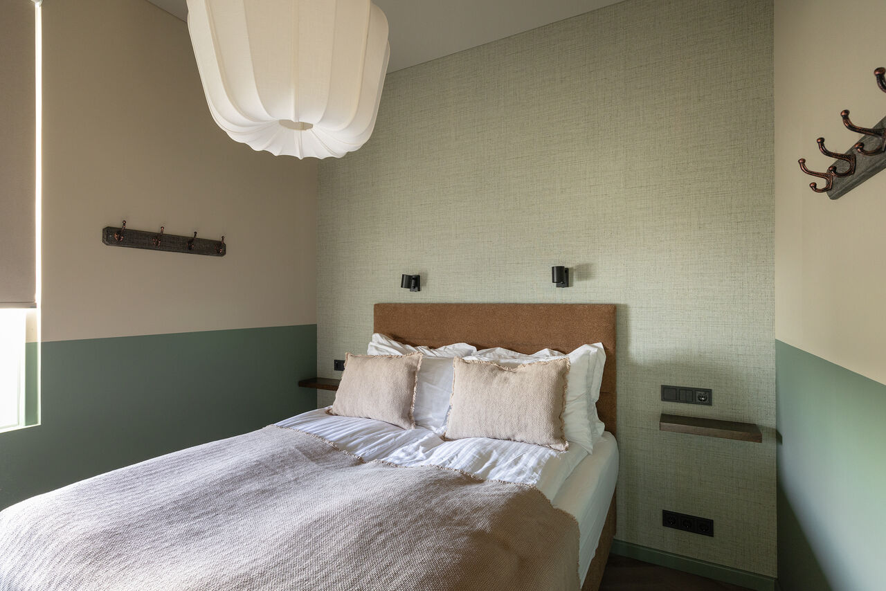 A double bed in a sage and cream bedroom