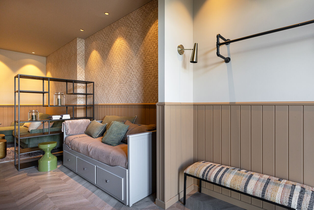 A daybed with cushions beside tall wall panelling