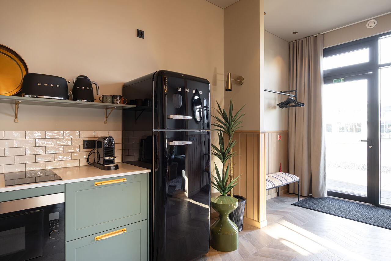 A kitchen with a black retro fridge next to a glazed door