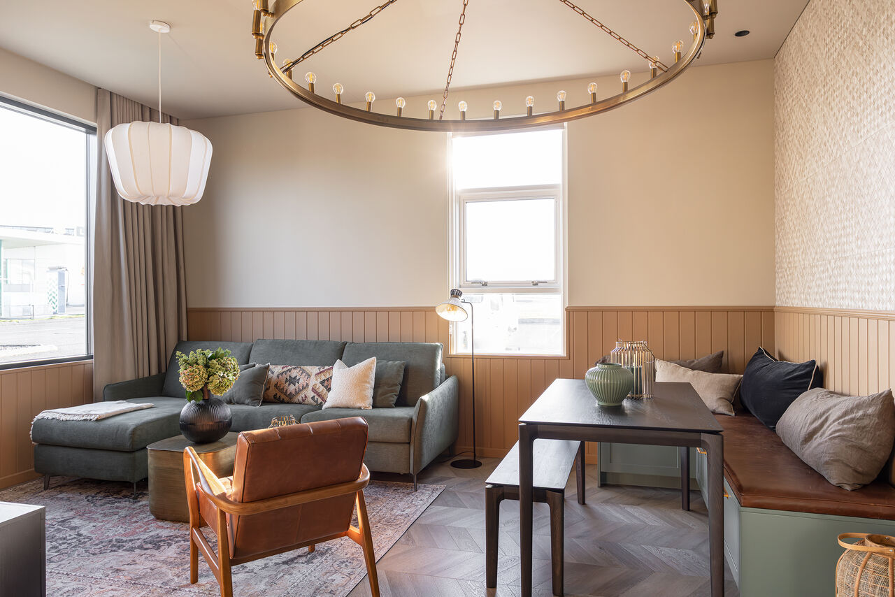 Apartment 3: a living room with a sofa, leather armchair and dining bench by two windows