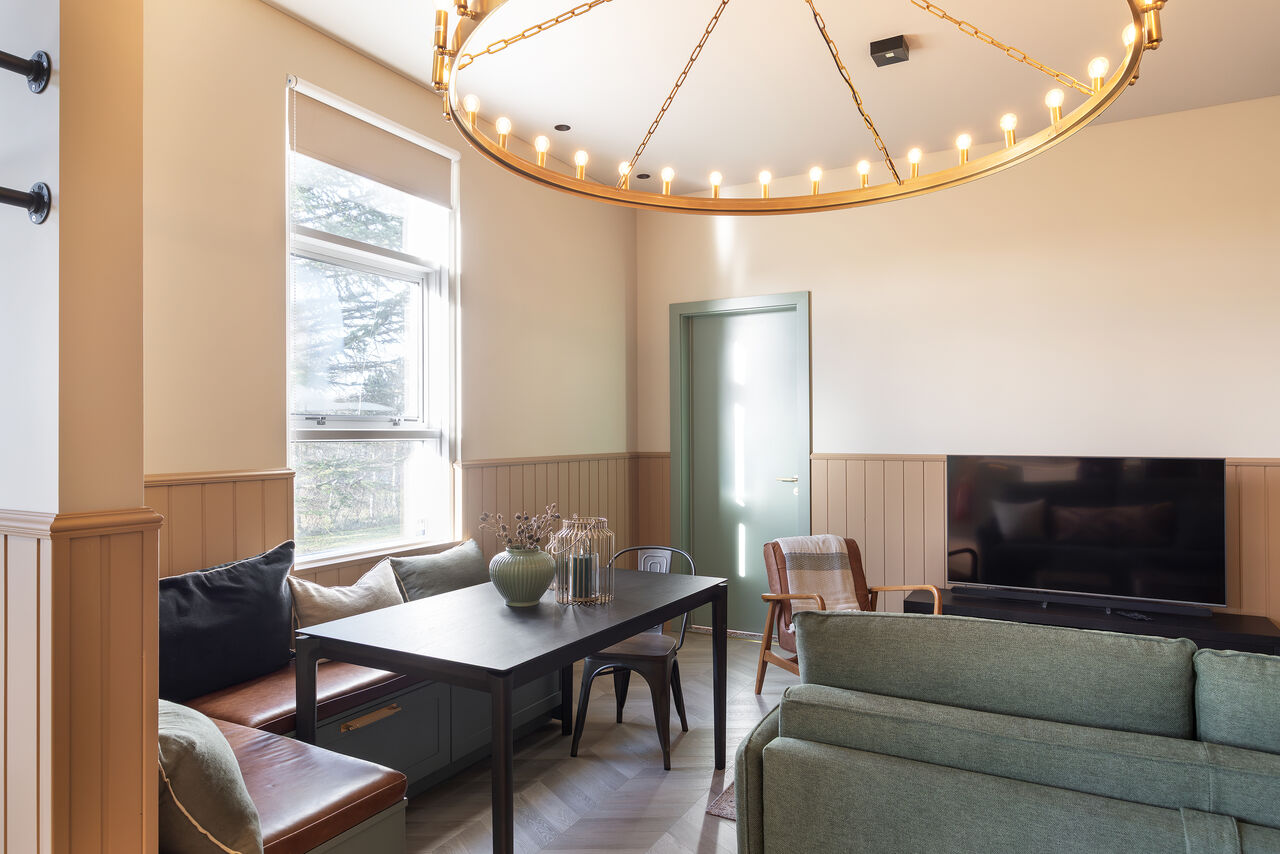 Apartment 4: a living room with a sofa, dining table and a window onto the garden side
