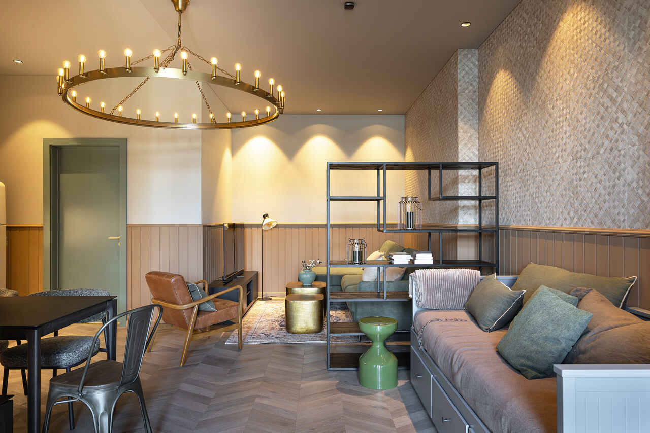 A one-bedroom living room with a daybed, sofa and dining corner under a brass chandelier
