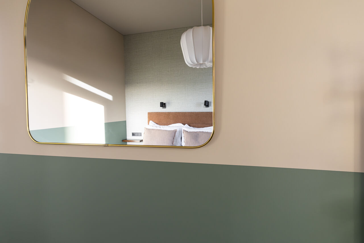 A brass-framed mirror reflecting the bedroom